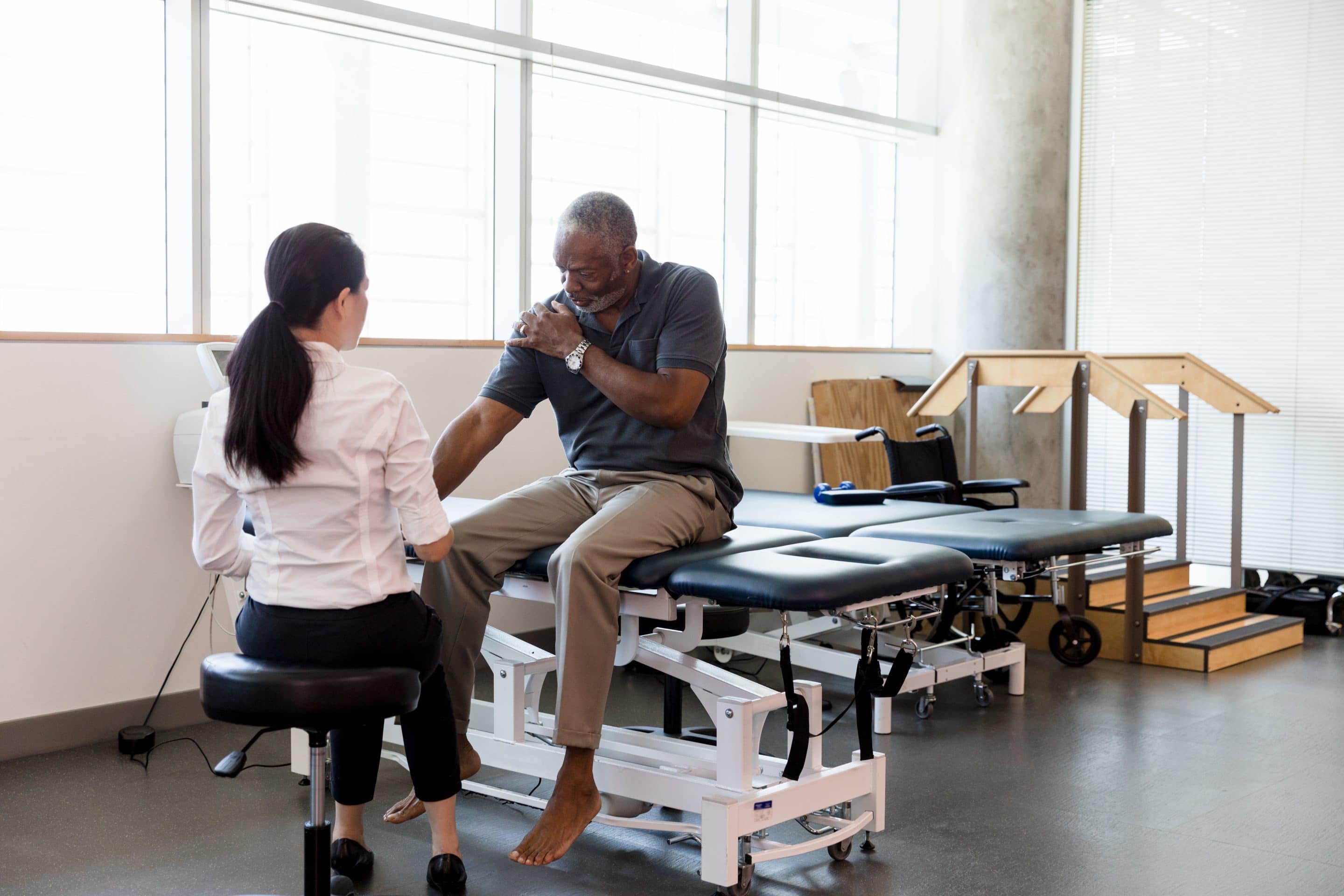 Senior man with an injured shoulder in rehab clinic